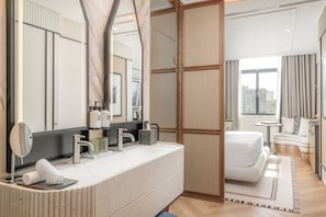 Une salle de bain d’hôtel moderne, dotée d’un grand miroir, d’un lavabo blanc et d’une baignoire.