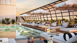 Een buitenzwembad, ligstoelen bij het zwembad