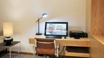 A neatly organized workspace with a desk, chair, lamp, and a computer monitor displaying a cityscape.