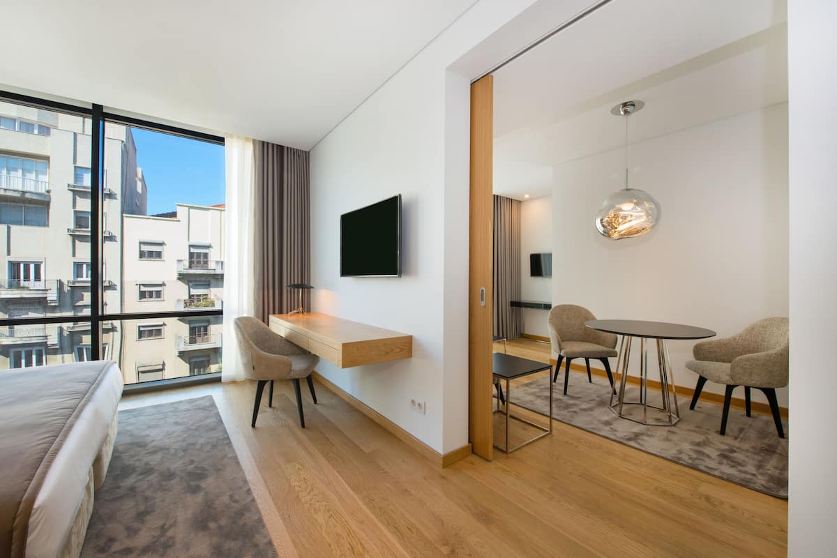 Een moderne hotelkamer met een groot raam, een bed, een bureau en een zithoek.