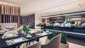 Un espace repas moderne doté d’un long comptoir, de sièges et d’un buffet.