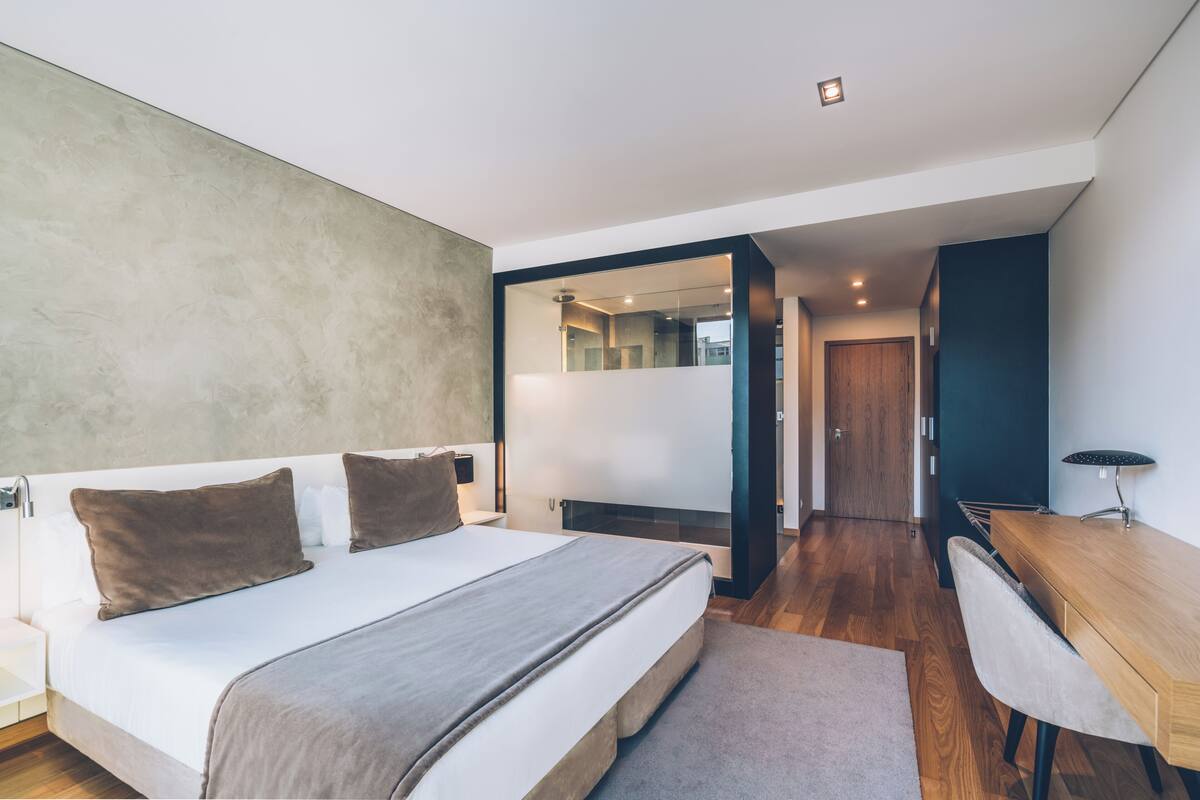 Een moderne slaapkamer met een groot bed, een bureau en een spiegel.