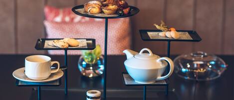 A tea service setup with pastries, a teapot, and a cup on a table.