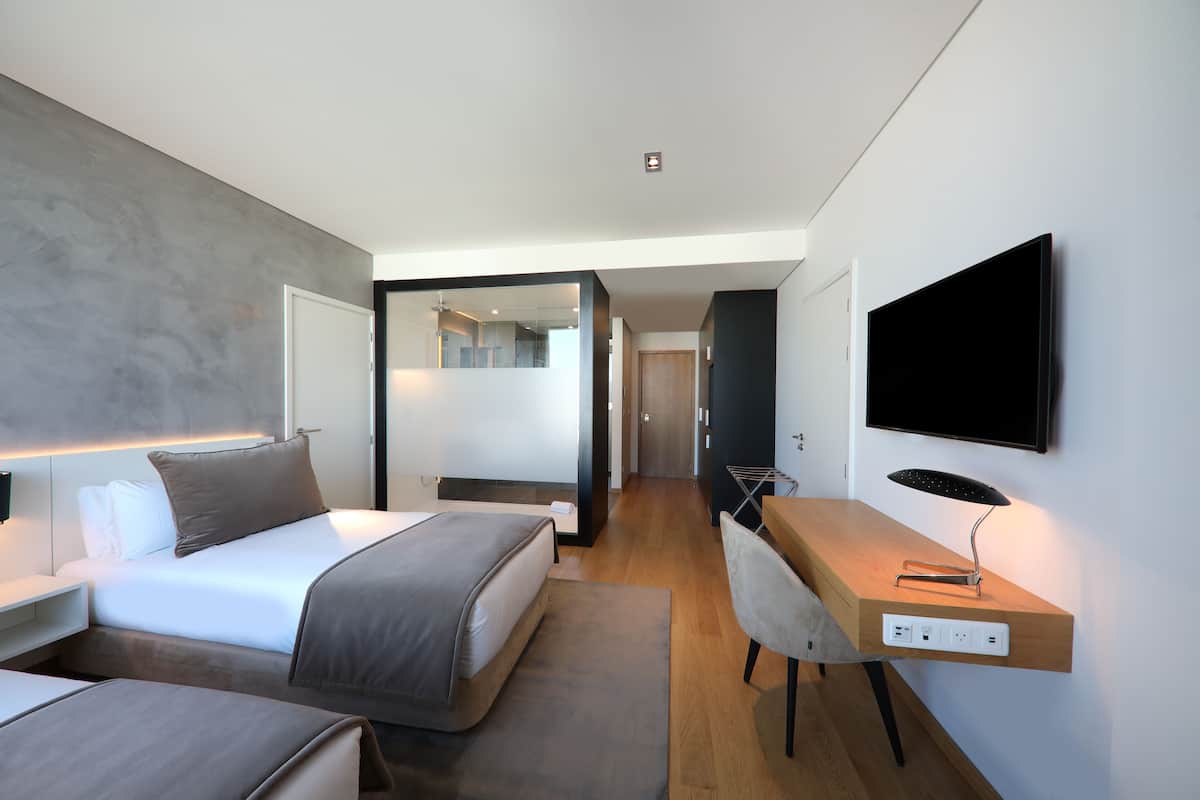 Een moderne hotelkamer met een bed, bureau en televisie.