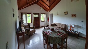 A spacious living area with a high wooden ceiling, a dining table with chairs, a sofa, and a television. - Cabañas Normana Inn (El Calafate)