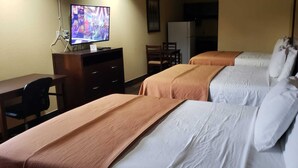 Una habitación de hotel con dos camas, un escritorio, un televisor y un refrigerador.