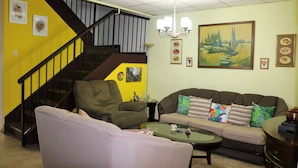 A living room with a staircase, a sofa set, a coffee table, and a painting on the wall. - The Illier's (Westmoorings)