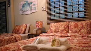 A hotel room with a bed, two pillows, a nightstand, a lamp, and a window with blinds. - The Illier's (Westmoorings)