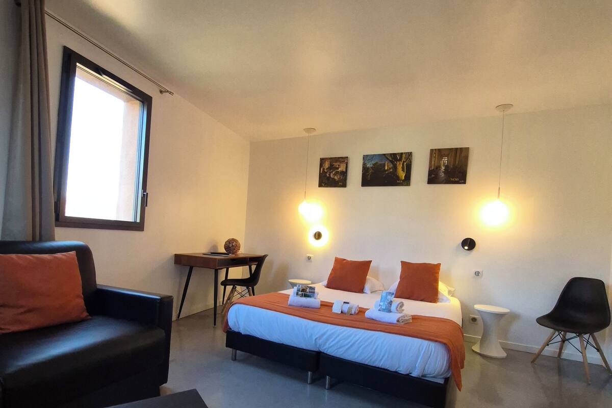 Een moderne hotelkamer met een bed, een bank, een bureau en een stoel.