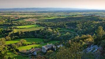 Un paysage rural avec un grand bâtiment entouré de champs et d’arbres.