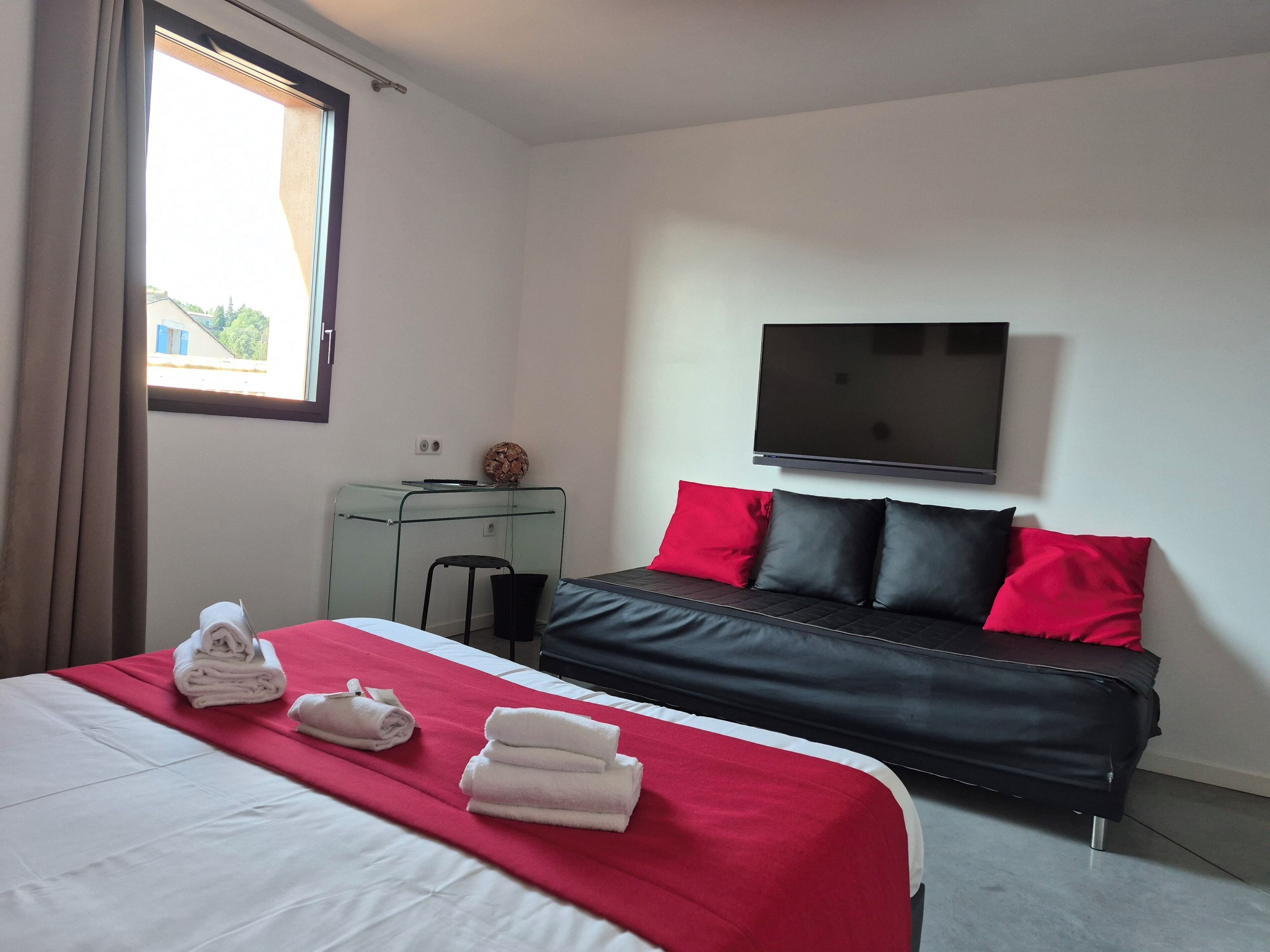 Una habitación de hotel con cama, escritorio, televisor y ventana.
