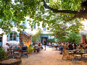 Un café en plein air, avec des tables et des chaises, entouré d’arbres et de bâtiments.