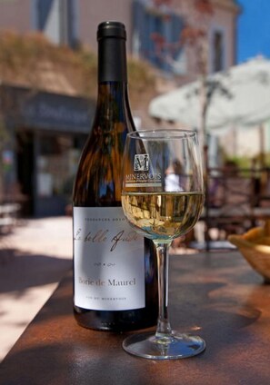 Une bouteille de vin et un verre sur une table, à l’extérieur.