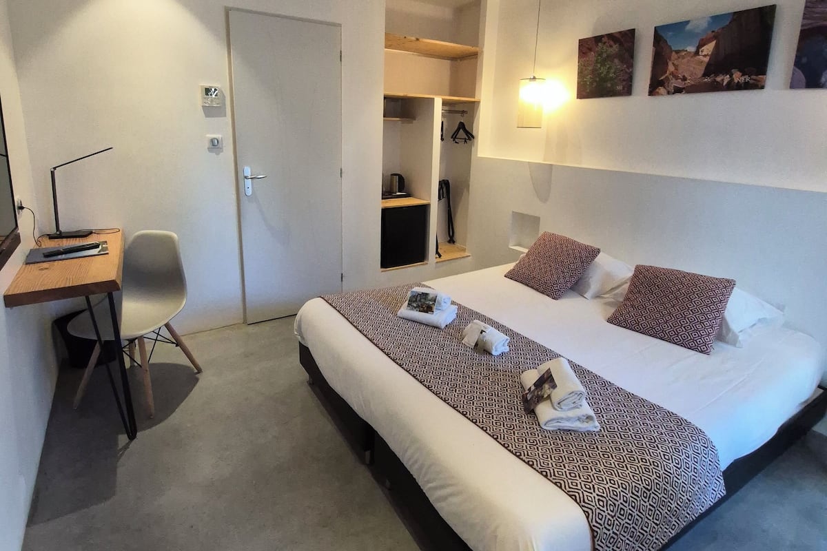 Een hotelkamer met een groot bed, een bureau en een stoel. Drie schilderijen hangen aan de muur.