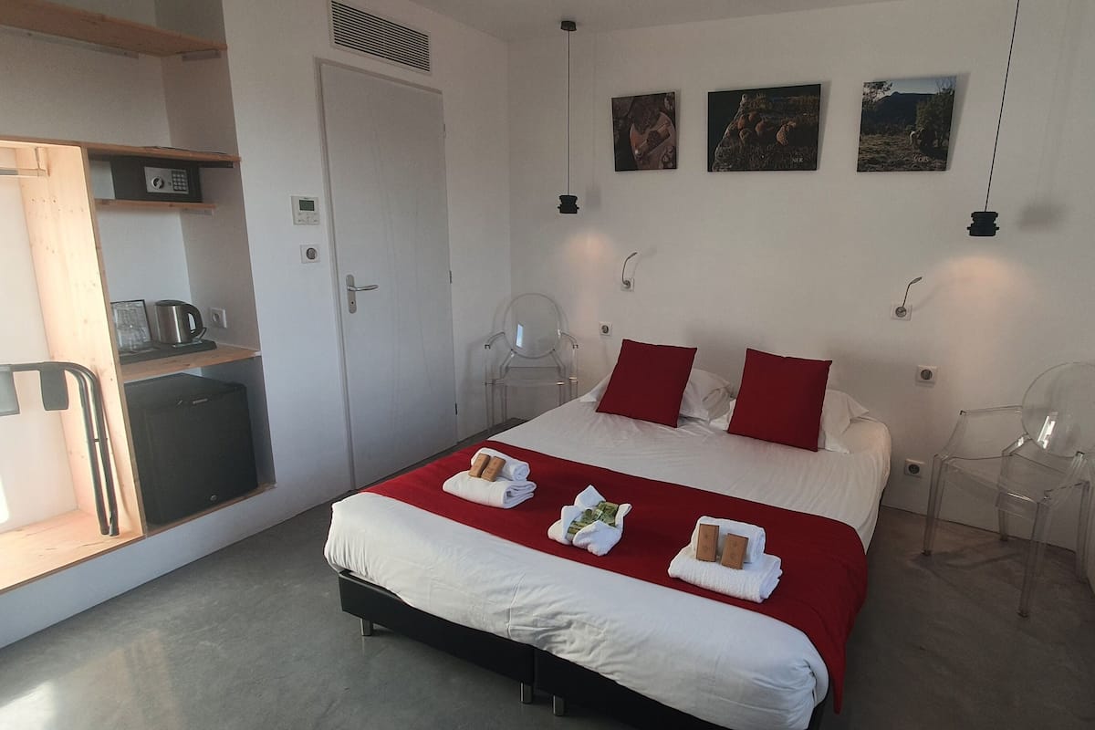Een hotelkamer met een bed, een bureau, een stoel en een kleine kitchenette.
