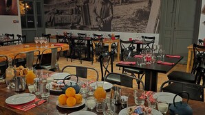 Een restaurant met houten tafels en stoelen, een muurschildering en diverse ontbijtartikelen op de tafels.