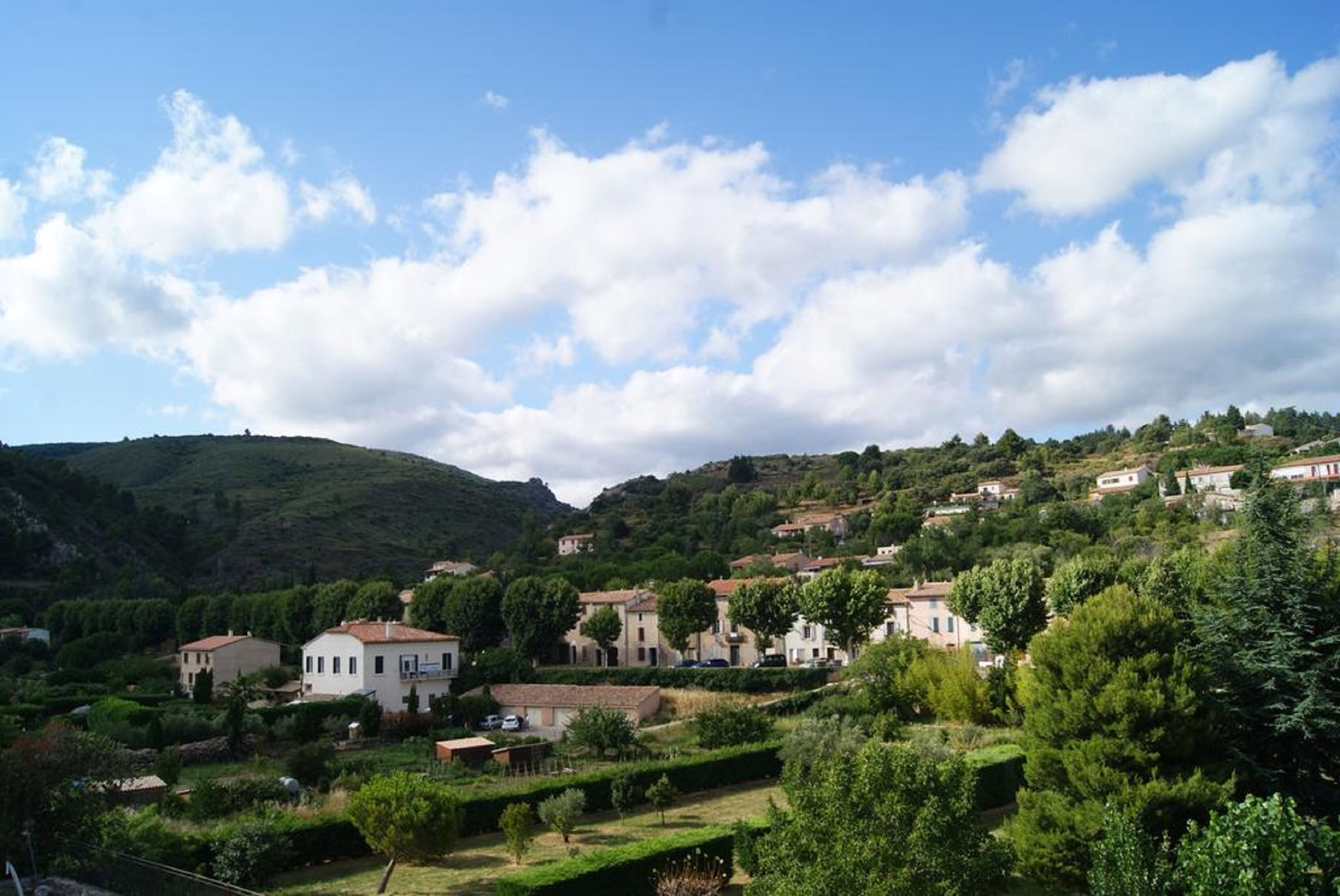 A hillside village with traditional architecture, terraced gardens, and a clear sky.