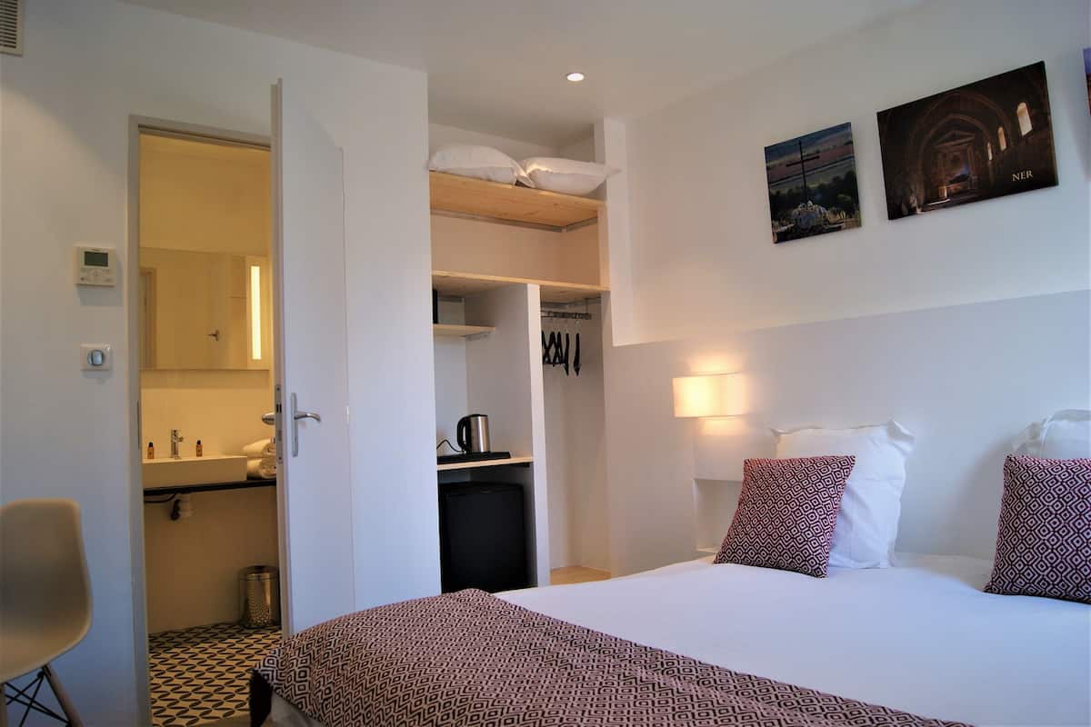 Een hotelkamer met een bed, een bureau, een stoel, een kledingkast en een badkamer.