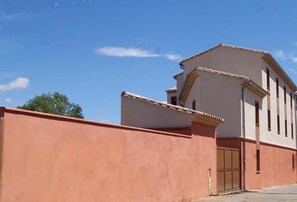 Un bâtiment à la façade beige, avec un mur rouge et une seule porte visible.