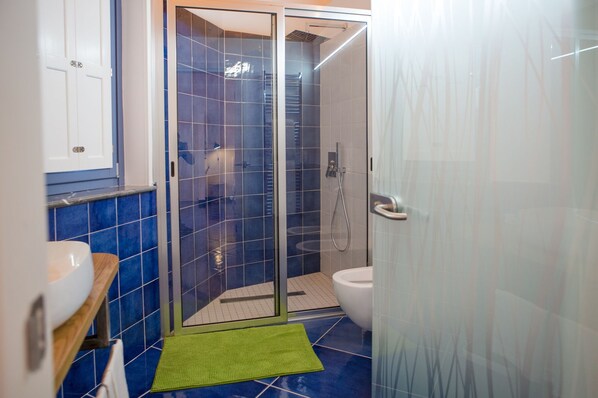 A modern bathroom with a glass-enclosed shower, a toilet, and a sink. - Ispani Inn Resort (Ispani)