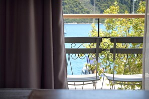 A balcony with a view of a body of water and trees. - Meltemi Hotel (Skiathos)