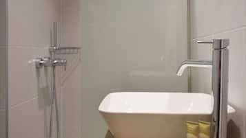 A bathroom with a white sink, a handheld showerhead, and toiletries on the countertop.