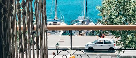 Un balcon avec vue sur la mer, une table avec une boisson et une pomme rouge.