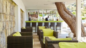 Una zona de bar con mobiliario de mimbre y un cantinero.