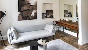 A modern living room with a sofa, a coffee table, and a side table. There is a large mirror and artwork on the wall. - Apartmani Orlando (Dubrovnik)