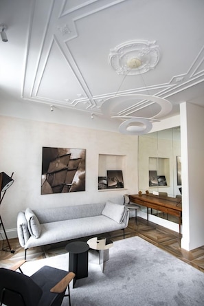 A modern living room with a sofa, a coffee table, and a side table. There is a large mirror and artwork on the wall. - Apartmani Orlando (Dubrovnik)