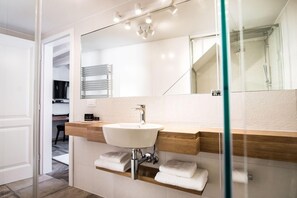 A modern bathroom with a large mirror, a white sink, and a glass shower enclosure. - Apartmani Orlando (Dubrovnik)