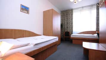 Quarto de hotel com duas camas, um guarda-roupa de madeira, uma cadeira e uma mesinha.