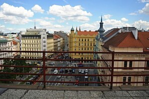 A cityscape with historic buildings, a prominent yellow building, and a clear sky. - Legie (Prague)