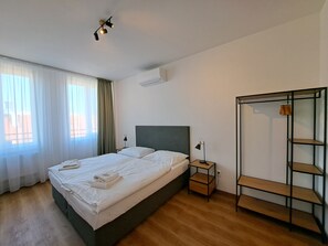 A hotel room with a bed, a bedside table, a wardrobe, and a window with curtains. - Legie (Prague)