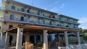 Un hotel de varios pisos con balcones, mobiliario exterior y un patio cubierto.