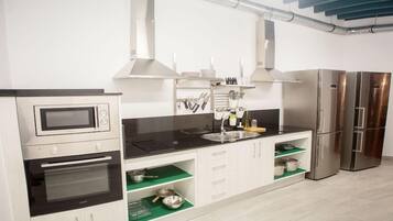 Una cocina moderna con electrodomésticos de acero inoxidable, encimera negra y armarios blancos.
