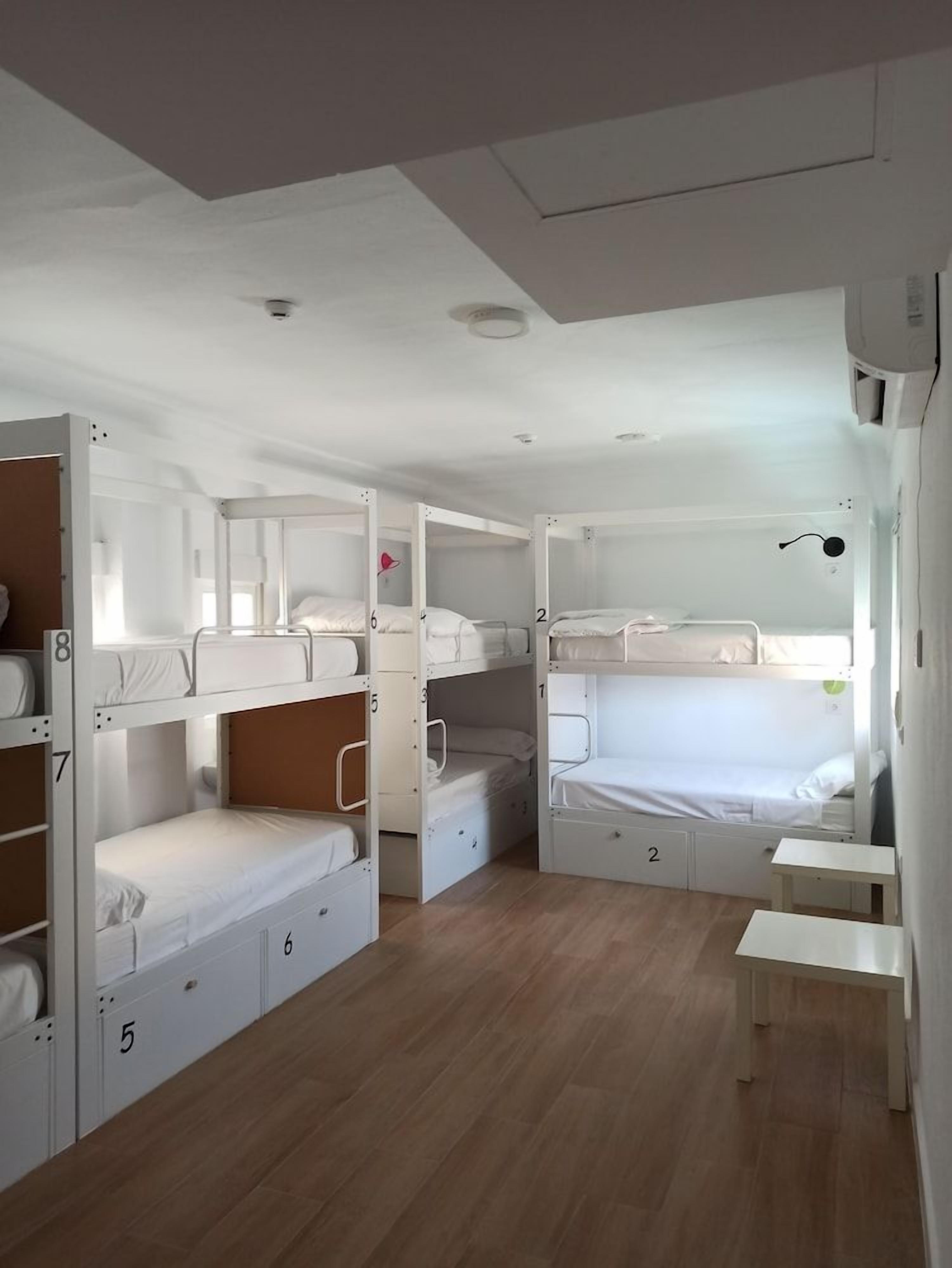 Un dormitorio con literas, una mesita pequeña y una unidad de aire acondicionado instalada en el techo.
