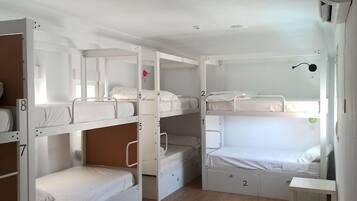 Un dormitorio con literas, una mesita pequeña y una unidad de aire acondicionado instalada en el techo.