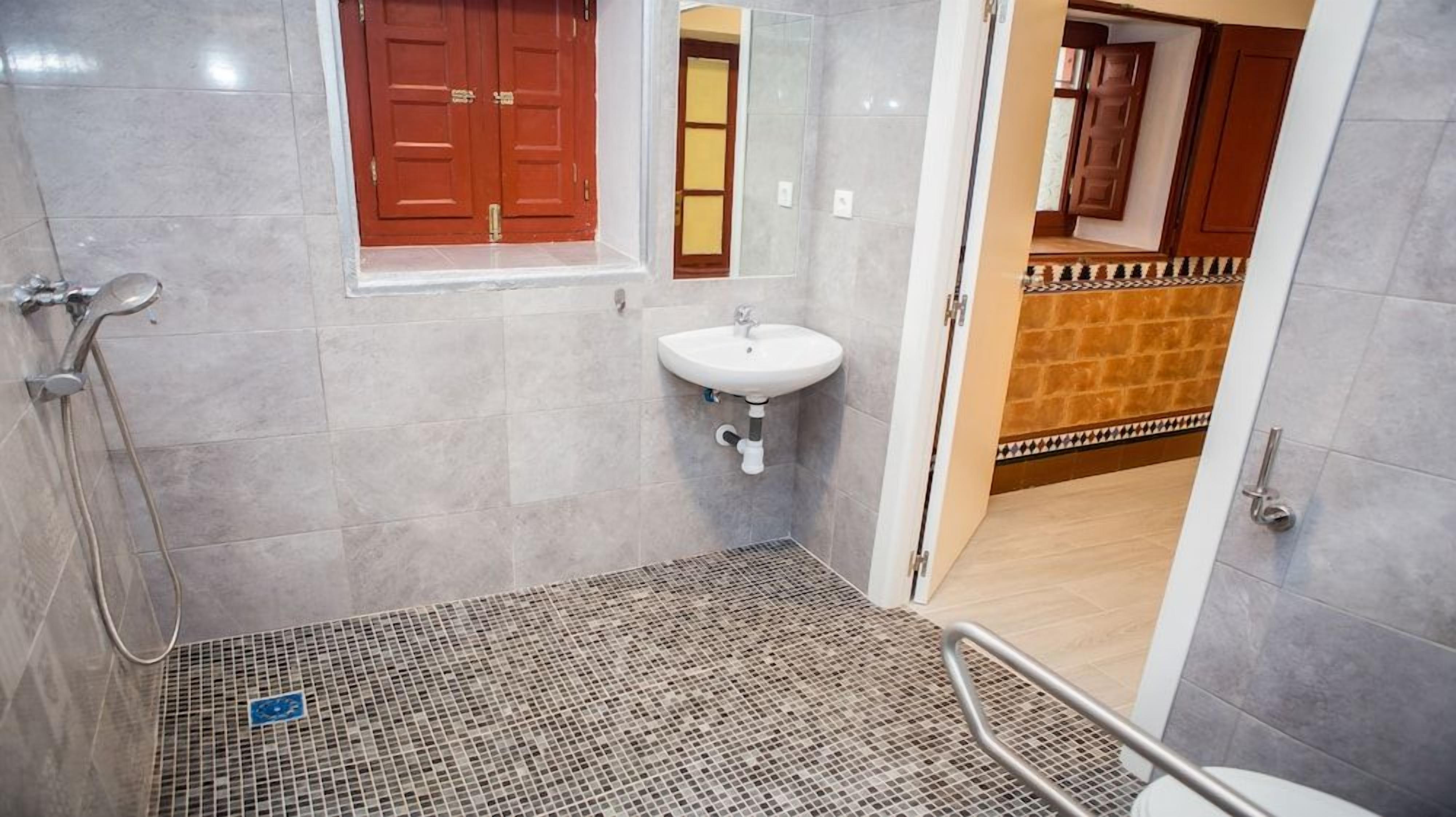 Un baño con ducha, lavamanos y piso de baldosas.