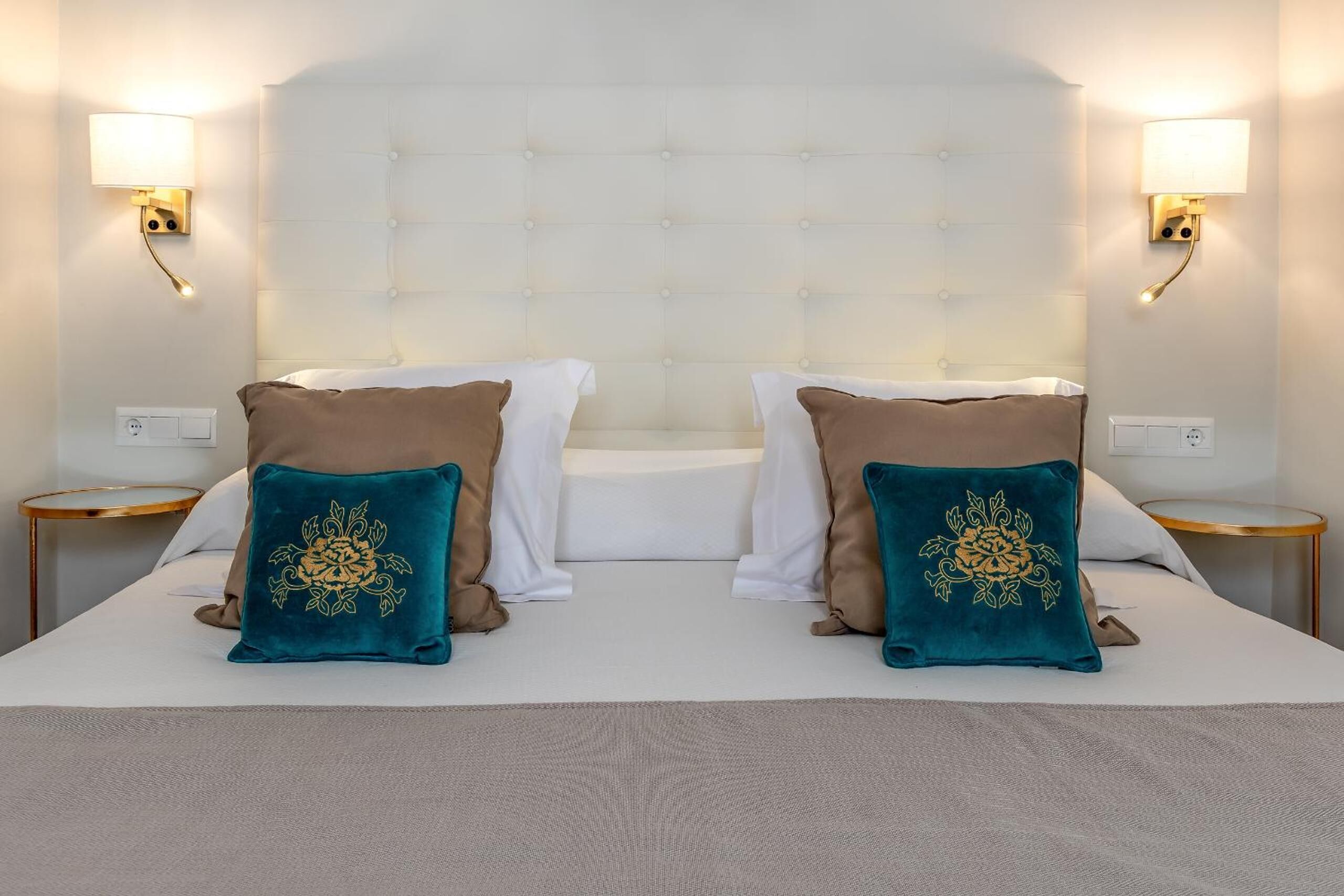 A hotel room with a large bed, two nightstands, and wall-mounted lamps.