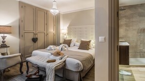 Un dormitorio con una cama grande, un banco, un tocador y una araña.