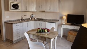 Una cocina compacta con encimera de granito, armarios blancos, microondas integrado y un refrigerador pequeño.