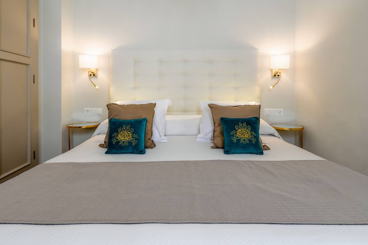 A double bed with a tufted headboard, two bedside tables, and decorative pillows.