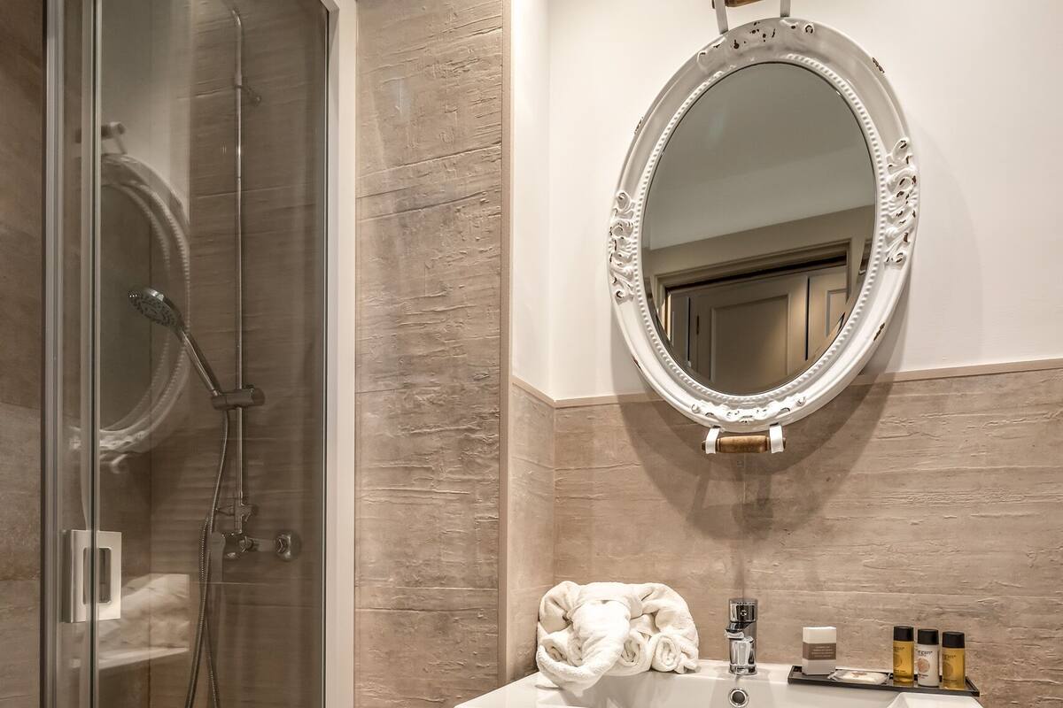 A modern bathroom with a glass-enclosed shower, a vanity with a mirror, and a wicker basket on the floor.