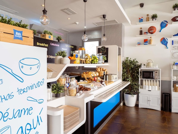 A breakfast buffet area with a variety of food items, a coffee machine, and a sign with a question in Spanish.