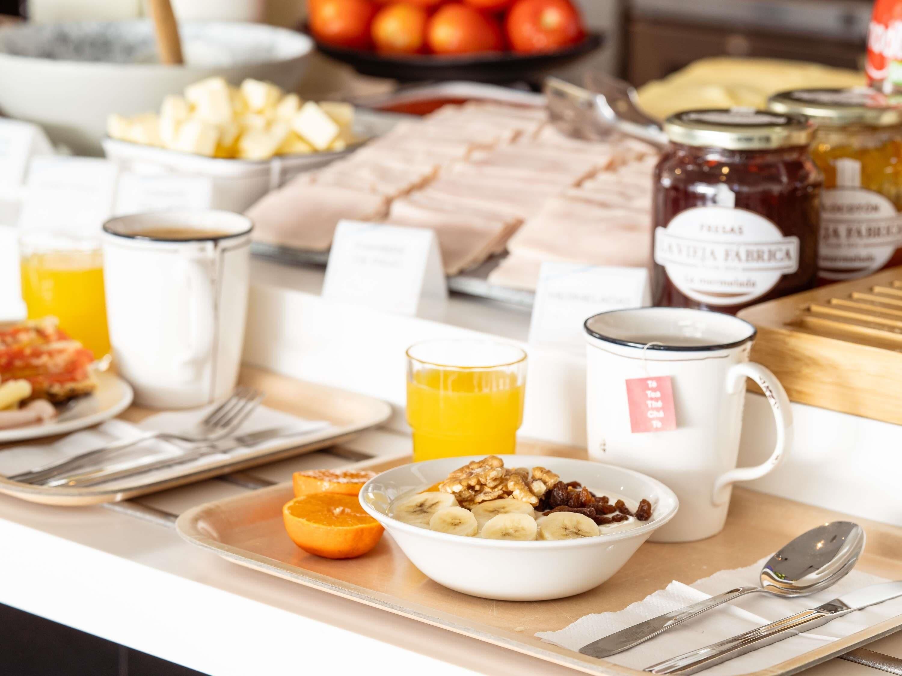 A breakfast buffet with various food items, a coffee station, and a fruit bowl.