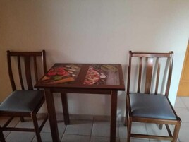 Una mesa de comedor con mantel floral y dos sillas de madera con asientos acolchados.