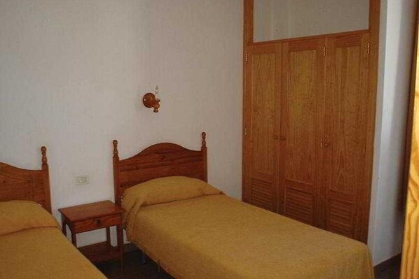 Ein Schlafzimmer mit zwei Holzbetten, einem kleinen Nachttisch und einem Holzschrank.