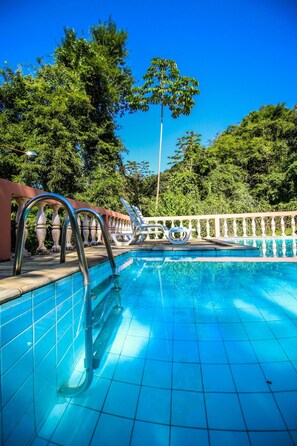 Una piscina al aire libre, sillones reclinables de piscina