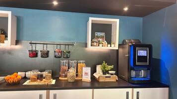 A kitchen with a coffee machine, jars of spices, and a hanging rack with kitchen utensils.